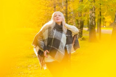 genç güzel artı boyutu kafkas kadın ekose yün poncho sonbahar parkta yürüyor