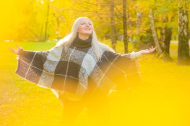 genç güzel artı boyutu kafkas kadın ekose yün poncho sonbahar parkta yürüyor