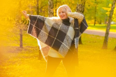 genç güzel artı boyutu kafkas kadın ekose yün poncho sonbahar parkta yürüyor