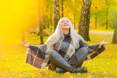 genç güzel artı boyutu kafkas kadın ekose yün poncho sonbahar parkta meditasyon
