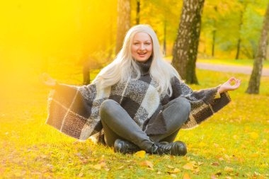 genç güzel artı boyutu kafkas kadın ekose yün poncho sonbahar parkta meditasyon