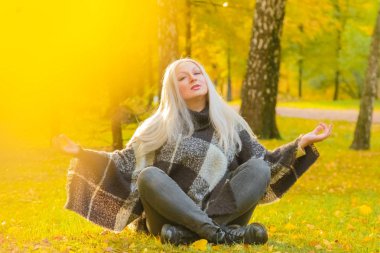 genç güzel artı boyutu kafkas kadın ekose yün poncho sonbahar parkta meditasyon