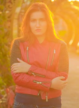 genç güzel artı kırmızı deri ceket li beyaz kadın gün batımı sonbahar parkında yürüyor