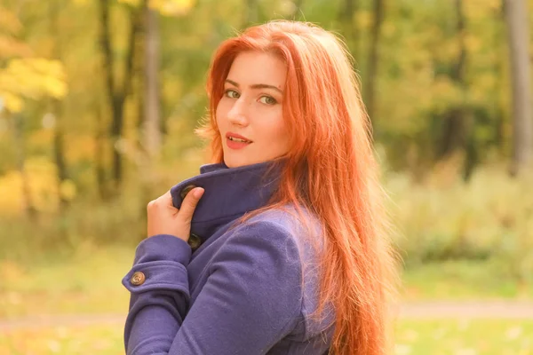 kırmızı saçlı mor ceket giyen genç güzel beyaz kadın ve sonbahar parkı yürüyor