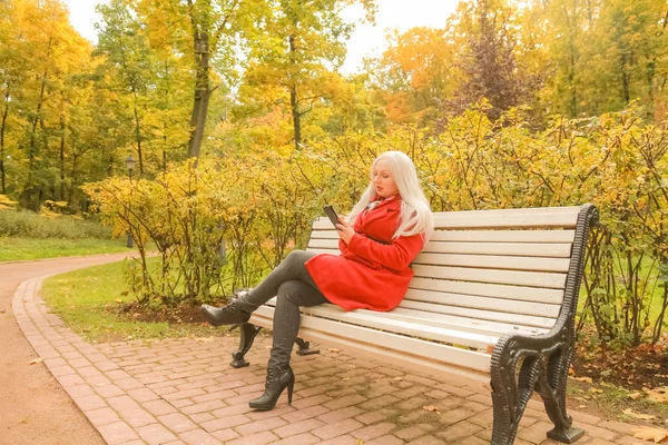 Joven bastante más tamaño mujer caucásica con teléfono inteligente en el parque de otoño —  Fotos de Stock