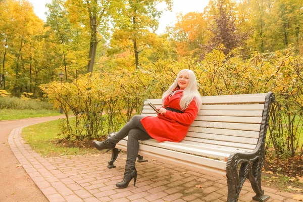 युवा सुंदर प्लस आकार काकेशियन महिला शरद ऋतु पार्क में बेंच पर बैठती है — स्टॉक फ़ोटो, इमेज