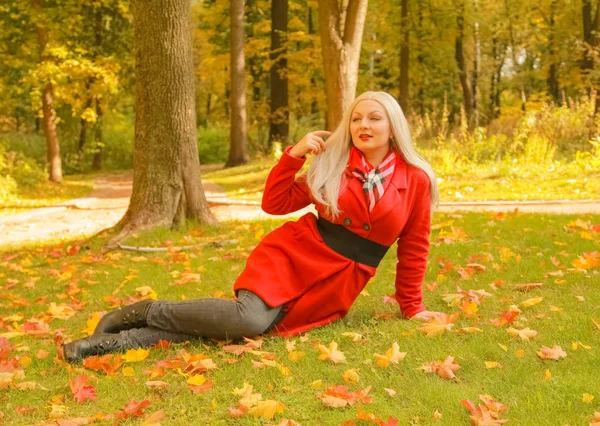 Молодая красивая белая блондинка в красном шерстяном пальто прогулки в осеннем парке — стоковое фото