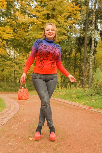 Молодая красивая белая женщина в апельсиновом лебедке гуляет в осеннем парке — стоковое фото