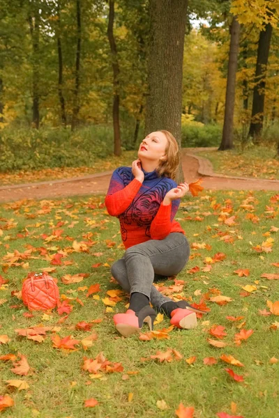 Junge hübsche Plus-Size-Kaukasierin in orangefarbenem Sweater spaziert durch Herbstpark — Stockfoto