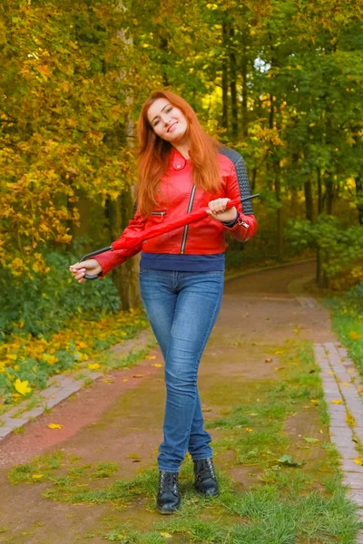 Genç güzel artı boyutu kafkas kadın sonbahar parkta kırmızı şemsiye ile yürüyor — Stok fotoğraf