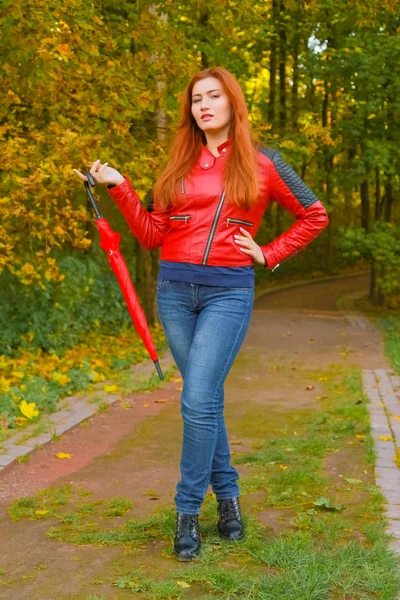 Joven bonita más tamaño mujer caucásica camina con paraguas rojo en el parque de otoño —  Fotos de Stock