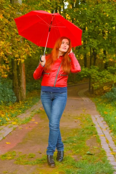 Jonge mooie plus size Kaukasische vrouw wandelingen met rode paraplu in herfst Park — Stockfoto