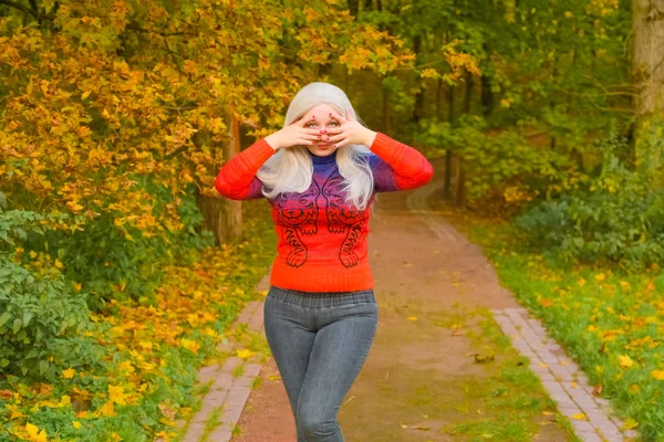 オレンジのファッションセーターで若いかわいいプラスサイズの白人女性が秋の公園を歩く — ストック写真