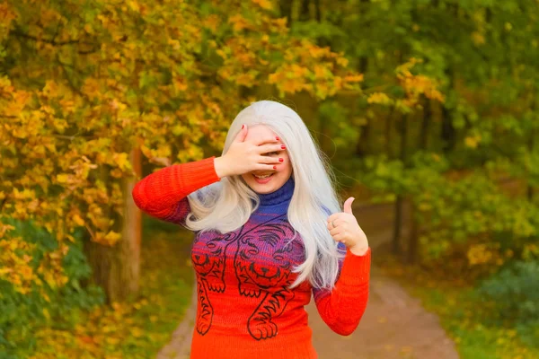 Молодая красивая белая женщина в оранжевом свитере в осеннем парке — стоковое фото