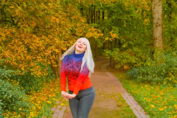 turuncu moda kazak genç güzel artı boyutu beyaz kadın sonbahar parkta yürüyor