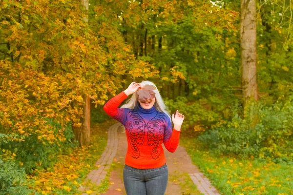 turuncu moda kazak genç güzel artı boyutu beyaz kadın sonbahar parkta yürüyor