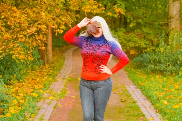 turuncu moda kazak genç güzel artı boyutu beyaz kadın sonbahar parkta yürüyor