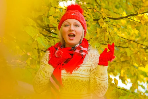 Jonge mooie plus size Kaukasische vrouw in rode hoed met pompom en gebreide handschoenen wandelingen in herfst Park — Stockfoto