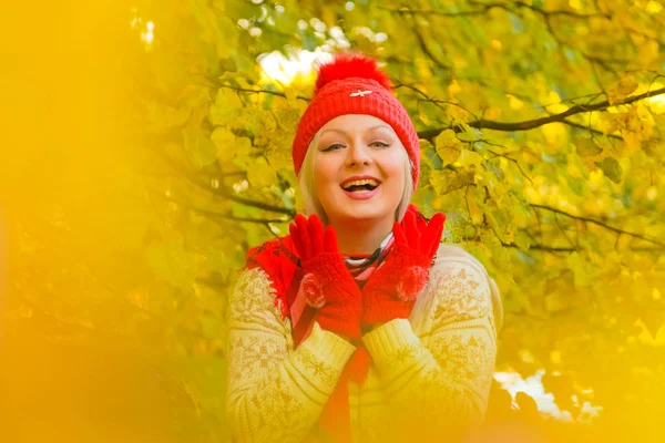 Jonge mooie plus size Kaukasische vrouw in rode hoed met pompom en gebreide handschoenen wandelingen in herfst Park — Stockfoto