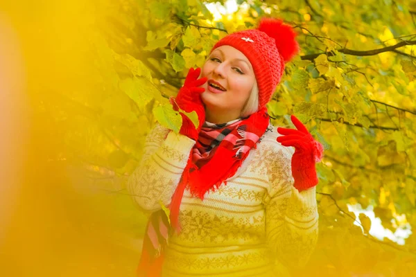 Jonge mooie plus size Kaukasische vrouw in rode hoed met pompom en gebreide handschoenen wandelingen in herfst Park — Stockfoto