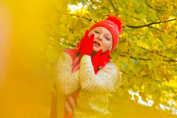 Jonge mooie plus size Kaukasische vrouw in rode hoed met pompom en gebreide handschoenen wandelingen in herfst Park — Stockfoto