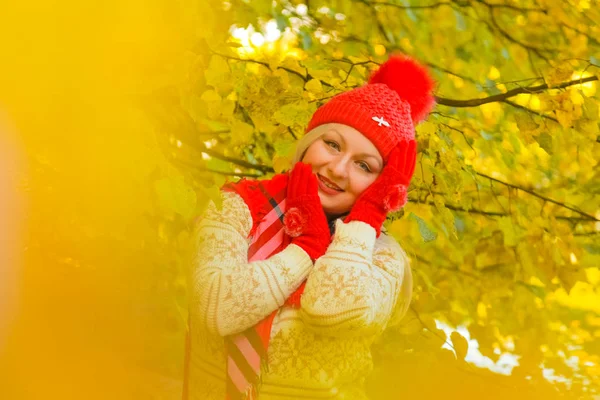 Jonge mooie plus size Kaukasische vrouw in rode hoed met pompom en gebreide handschoenen wandelingen in herfst Park — Stockfoto