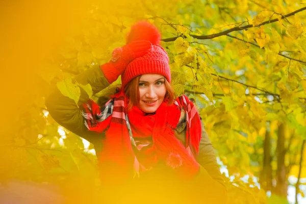 genç güzel artı büyük beyaz kadın pompom ve örme eldiven ile kırmızı şapkalı sonbahar parkta yürüyor