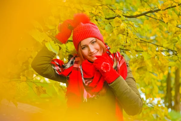 genç güzel artı büyük beyaz kadın pompom ve örme eldiven ile kırmızı şapkalı sonbahar parkta yürüyor