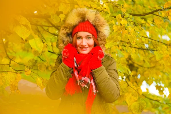 Junge hübsche Plus-Size-Kaukasierin in roter Mütze mit Bommel und Strickhandschuhen spaziert im Herbstpark — Stockfoto