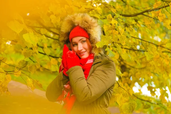genç güzel artı büyük beyaz kadın pompom ve örme eldiven ile kırmızı şapkalı sonbahar parkta yürüyor