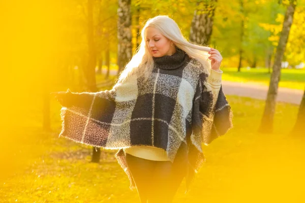 Jonge mooie plus size Kaukasische vrouw geruite wollen poncho wandelingen in herfst Park — Stockfoto