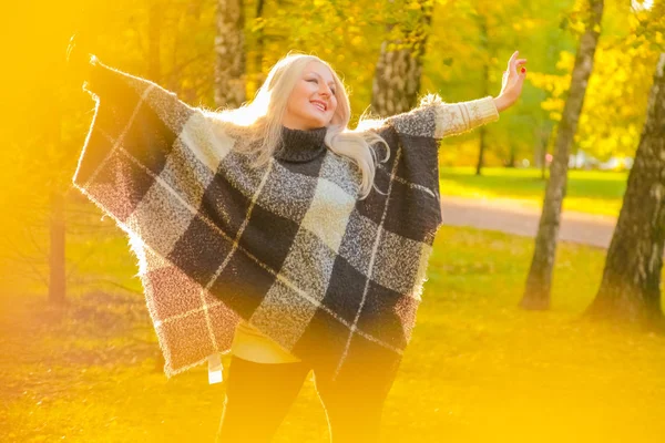 Fiatal csinos molett kaukázusi nő kockás gyapjú poncsó sétál ősszel Park — Stock Fotó