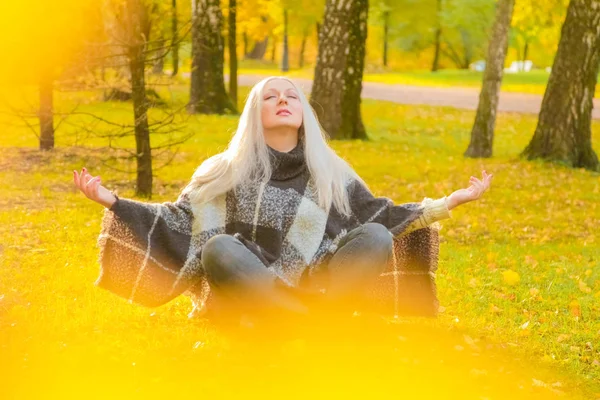 Молодая красивая белая женщина в клетчатом пончо в осеннем парке — стоковое фото