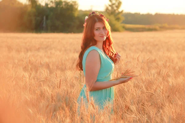 Mädchen in Kleid zu Fuß in goldenen reifen Weizenfeld bei Sonnenuntergang — Stockfoto