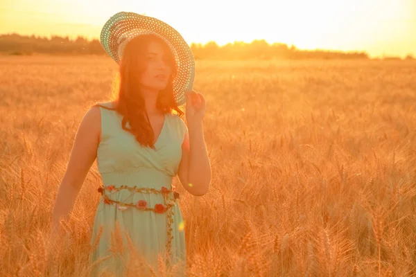 Дівчина в сукні, що йде в золотому стиглому пшеничному полі на заході сонця — стокове фото