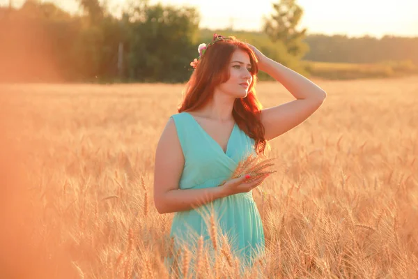 Meisje in jurk wandelen in gouden rijpe tarwe veld bij zonsondergang — Stockfoto