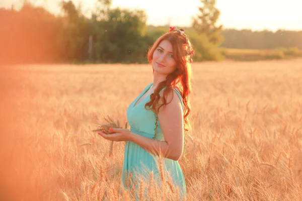 Dziewczyna w sukni chodzenie w Złotym dojrzałym polu pszenicy o zachodzie słońca — Zdjęcie stockowe