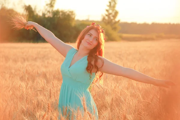 Menina de vestido andando no campo de trigo maduro dourado ao pôr do sol — Fotografia de Stock