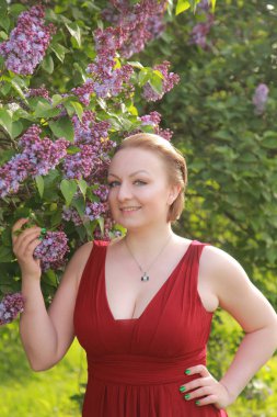 leylak ağacı yakınında uzun kırmızı elbise güzel artı boyutu kısa saçlı kadın