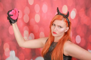 Kırmızı arka plan üzerinde kalp şekli ile pembe peluş oyuncak ile Devil kız