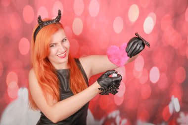 Kırmızı arka plan üzerinde kalp şekli ile pembe peluş oyuncak ile Devil kız