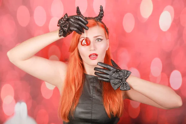 Mode Pretty ung kvinna med röd Lollipop hjärta bär svart läder klänning och djävul horn — Stockfoto