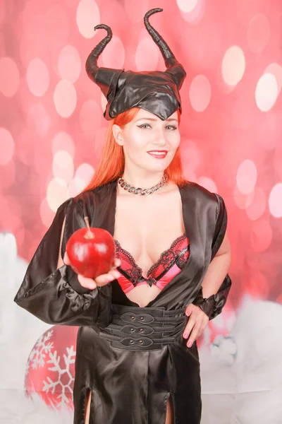 şeytan boynuzları ile seksi siyah elbise kızıl saçlı kız ayartma ve baştan çıkarma ile kırmızı elma tutar