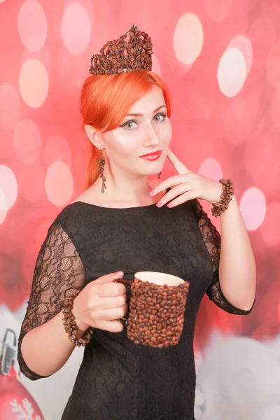 Kadın kahve fincanı lezzetli aroması zevk ve kırmızı noel arka plan üzerinde kahve çekirdekleri ile takı giymek — Stok fotoğraf