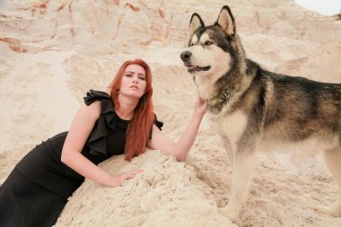 Komik en iyi arkadaş kavramı. Mutlu genç kadın kişi açık havada büyük köpek malamute ile çölde yürüyor