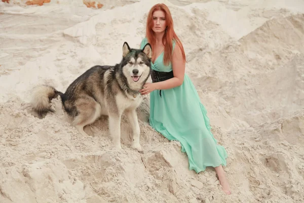 Concepção engraçada dos melhores amigos. Jovem feliz pessoa feminina caminha no deserto com cão grande malamute ao ar livre — Fotografia de Stock