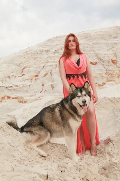Забавная концепция лучших друзей. Счастливая молодая женщина гуляет по пустыне с большой собакой маламут на открытом воздухе — стоковое фото