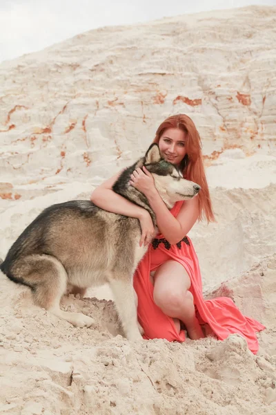 Grappig beste vrienden concept. Gelukkige jonge vrouwelijke persoon loopt in de woestijn met grote hond Malamute buitenshuis — Stockfoto