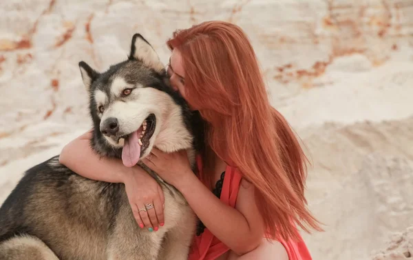 Grappig beste vrienden concept. Gelukkige jonge vrouwelijke persoon loopt in de woestijn met grote hond Malamute buitenshuis — Stockfoto