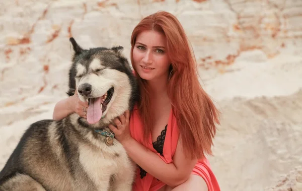 Grappig beste vrienden concept. Gelukkige jonge vrouwelijke persoon loopt in de woestijn met grote hond Malamute buitenshuis — Stockfoto